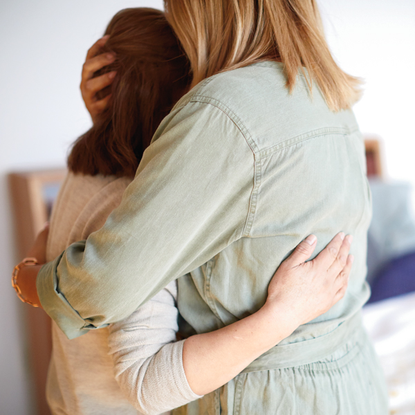 Two women embracing one another in comfort during tough time